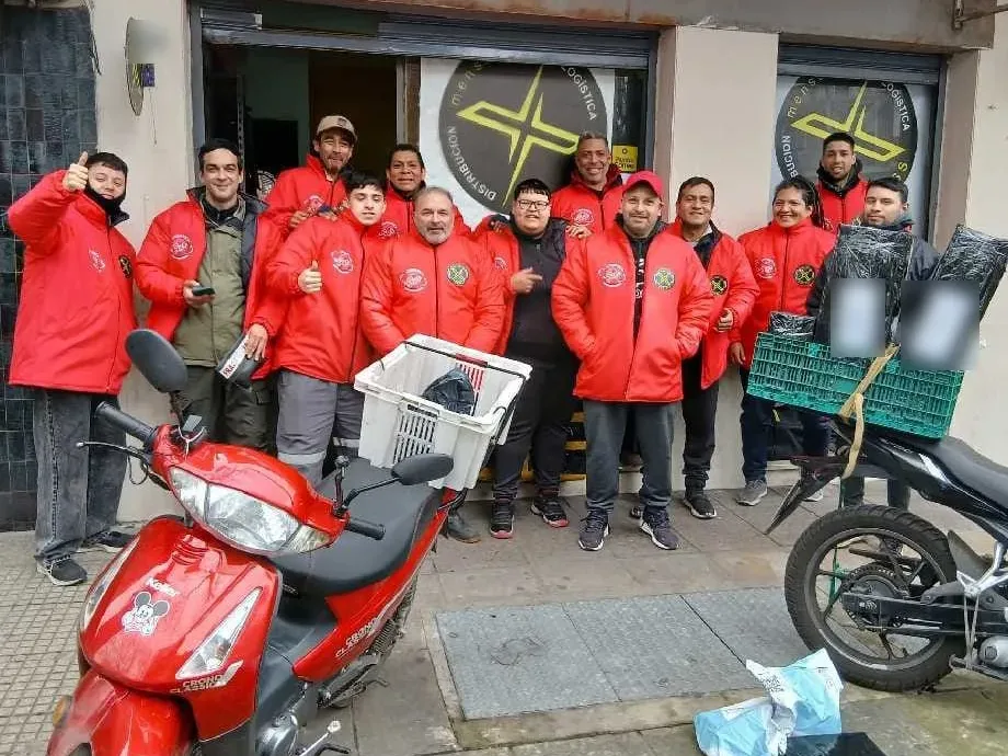 Equipo de Logística Norte frente al local, con motos y cajones de reparto